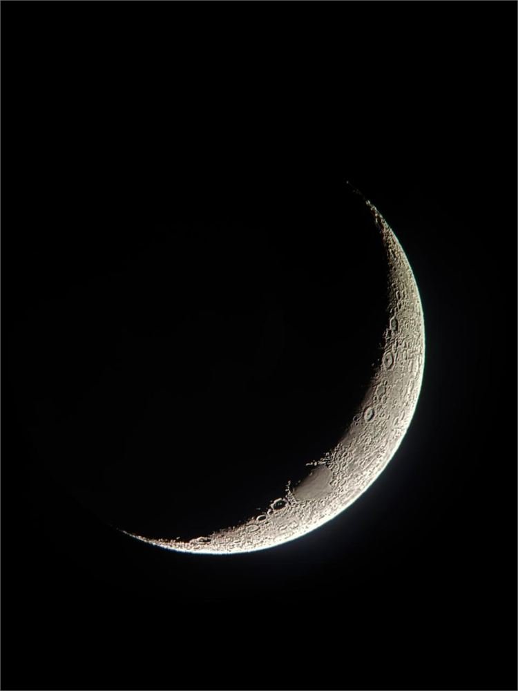 A waxing crescent moon in sharp detail, craters visible along the terminator